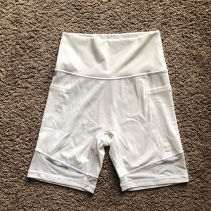 White biker shorts with mesh around the bottom and pockets